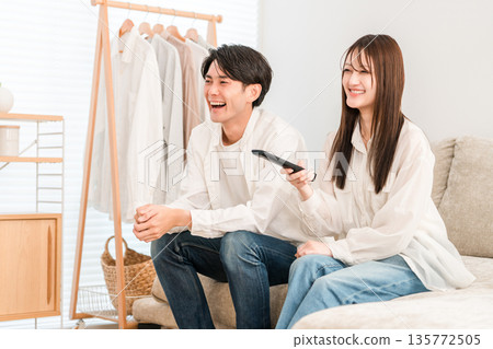 Young Asian couple watching TV on the sofa in the living room at home 135772505