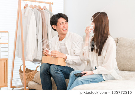 一對年輕的亞洲夫婦在家裡的客廳沙發上看電視，兩人（親密互動，流淚，淚流滿面） 135772510