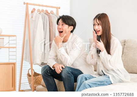 Young Asian couple watching TV in the living room (surprised, surprised, cheering, cheering) Young Asian couple watching TV in the living room (surprised, surprised, cheering, cheering) 135772688