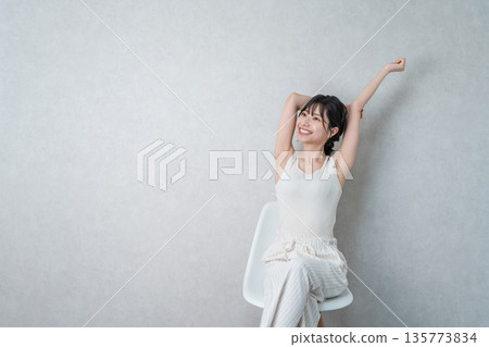 亞洲女人坐在家裡的椅子上,伸懶腰,深呼吸 亞洲女人坐在家裡的椅子上,伸懶腰,深呼吸 135773834