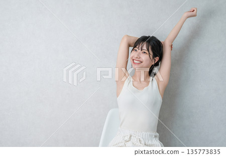 亞洲女人坐在家裡的椅子上,伸懶腰,深呼吸 亞洲女人坐在家裡的椅子上,伸懶腰,深呼吸 135773835