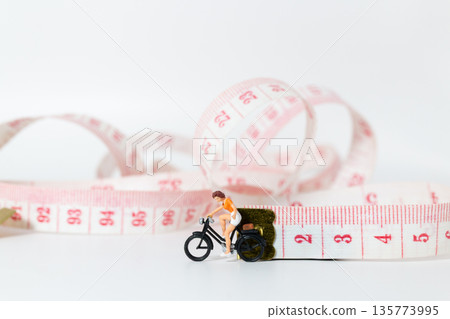 Miniature Woman Cycling on Measuring Tape for Fitness Concept Miniature Woman Cycling on Measuring Tape for Fitness Concept 135773995