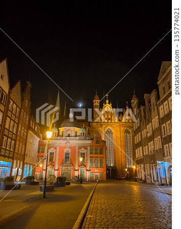 Historic building in a city square at night with lights and towers Historic building in a city square at night with lights and towers 135774021