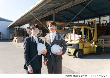 Men in suits standing in front of a lumber mill 135774273
