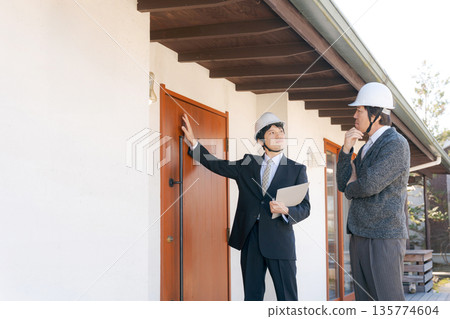 Men in suits having a meeting in front of a house Men in suits having a meeting in front of a house 135774604