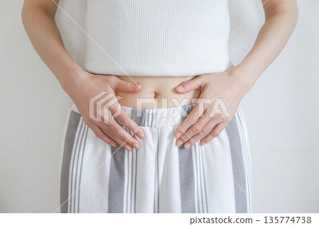 一位女士摀著肚子,露出腹部。飲食 一位女士摀著肚子,露出腹部。飲食 135774738
