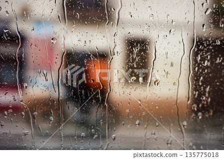 Rain drops on window with blurred city background Rain drops on window with blurred city background 135775018