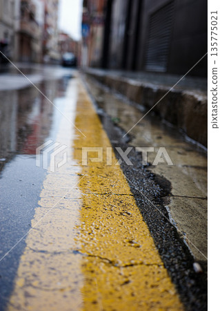 Wet urban street with yellow line after rain 135775021