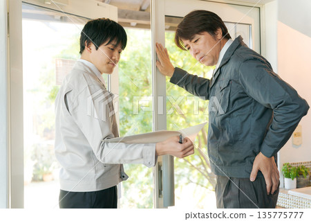 幾個穿著工作服的男人在玻璃門前開會。 135775777