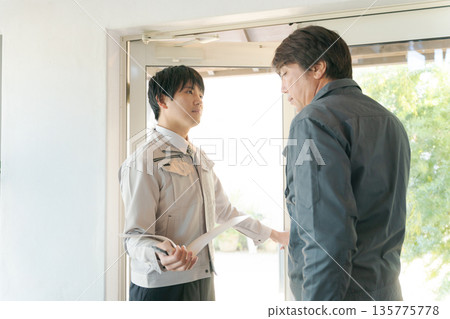 幾個穿著工作服的男人在玻璃門前開會。 幾個穿著工作服的男人在玻璃門前開會。 135775778