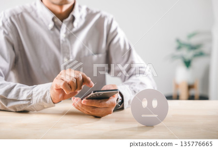 Customer submitting neutral feedback, completing service quality satisfaction survey on smartphone, showing neutral icon for customer experience evaluation 135776665