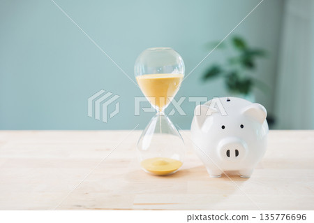 Save money and invest dividend income interest fund in pig piggy bank, hourglass with yellow sand on wooden table shows time management and productivity for long term financial goals Save money and invest dividend income interest fund in pig piggy bank, hourglass with yellow sand on wooden table shows time management and productivity for long term financial goals 135776696