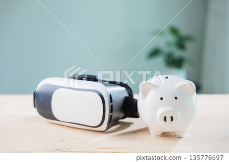 White piggy bank and vr headset on wooden surface represent metaverse banking, money saving, virtual reality casino, ar technology, digital investment, future finance growth White piggy bank and vr headset on wooden surface represent metaverse banking, money saving, virtual reality casino, ar technology, digital investment, future finance growth 135776697