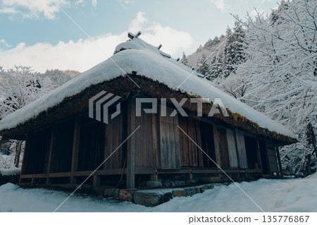 一棟老房子，茅草屋頂上覆蓋著積雪。 135776867