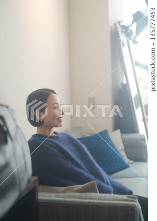 A woman sitting on a sofa and relaxing A woman sitting on a sofa and relaxing 135777453