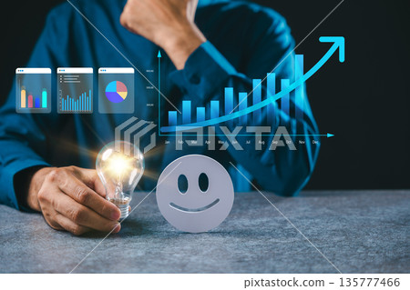 Businessman analyzes customer experience satisfaction while holding glowing light bulb next to happy face, data graphs show positive feedback results and company growth success Businessman analyzes customer experience satisfaction while holding glowing light bulb next to happy face, data graphs show positive feedback results and company growth success 135777466