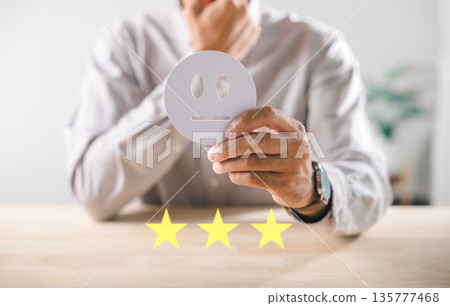 Customer provides neutral feedback using hand holding emoji icon representing service satisfaction survey for detailed quality evaluation with three star rating Customer provides neutral feedback using hand holding emoji icon representing service satisfaction survey for detailed quality evaluation with three star rating 135777468