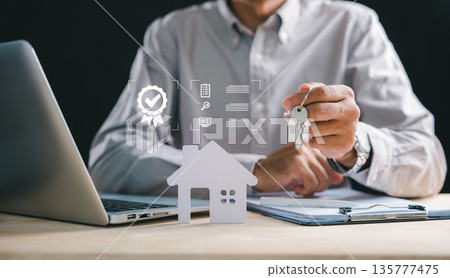 Man holding house keys, symbol of real estate home property purchase, seeking mortgage loan financing, reviewing documents for new acquisition, investment using laptop, ensuring quality property 135777475