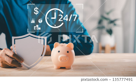 Shield protects piggy bank money saving plan for financial insurance, person holds white paper security symbol to save finance stability with digital clock and graph chart 135777491