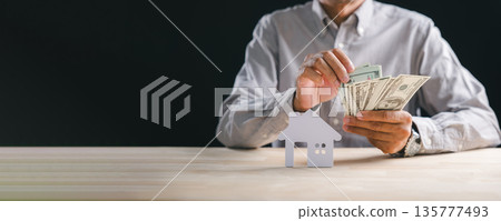 Home property investment concept, person carefully counting cash money for real estate purchase or mortgage payment, planning funds for new house or estate 135777493