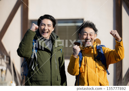 Fun image of tourists climbing mountains from mountain hut, fist pump Fun image of tourists climbing mountains from mountain hut, fist pump 135777892