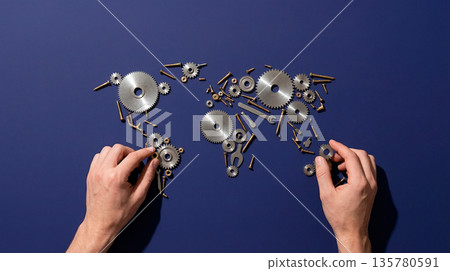 Hands assembling a world map made of gears, screws, and wrenches on a blue background Hands assembling a world map made of gears, screws, and wrenches on a blue background 135780591