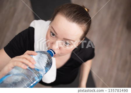 Woman Drinks Water After Workout to Stay Hydrated in Gym Setting During Daytime Woman Drinks Water After Workout to Stay Hydrated in Gym Setting During Daytime 135781490