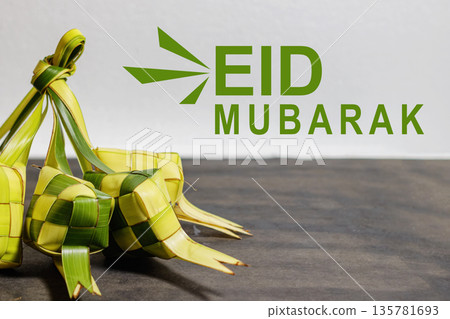 Eid Mubarak Greeting with Traditional Ketupat and Palm Leaves. Eid Mubarak. Islamic Festival elements. Asian Culture. High quality photo Eid Mubarak Greeting with Traditional Ketupat and Palm Leaves. Eid Mubarak. Islamic Festival elements. Asian Culture. High quality photo 135781693