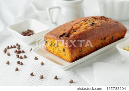 Cake with chocolate pieces on a white table. 135782204