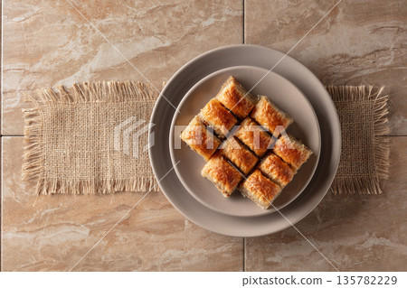 Baklava with walnuts on a beige plate. Baklava with walnuts on a beige plate. 135782229