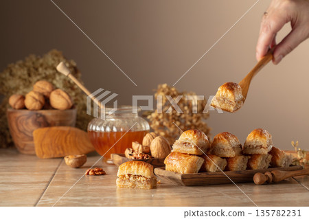 Baklava with walnuts and honey on a beige background. Baklava with walnuts and honey on a beige background. 135782231
