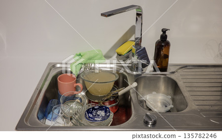 Dirty dishes in sink on the kitchen Dirty dishes in sink on the kitchen 135782246