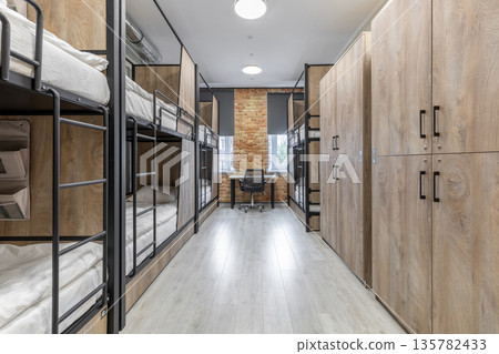 Modern loft hostel dormitory with bunk beds and wooden lockers 135782433