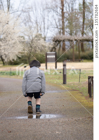 一個男孩飛過公園裡的水坑,然後降落 一個男孩飛過公園裡的水坑,然後降落 135782684