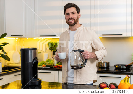 Middle-aged man enjoying fresh coffee aroma in home kitchen before breakfast morning with calm smile 135783403