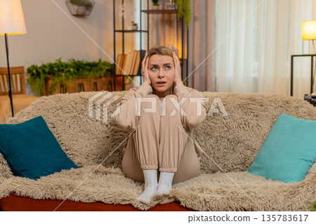 Adult sad woman showing visible stress, tension and emotional irritated, fatigue at home on sofa Adult sad woman showing visible stress, tension and emotional irritated, fatigue at home on sofa 135783617
