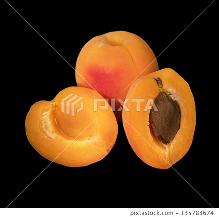 Ripe apricot fruits whole and in pieces on a black background isolated 135783674