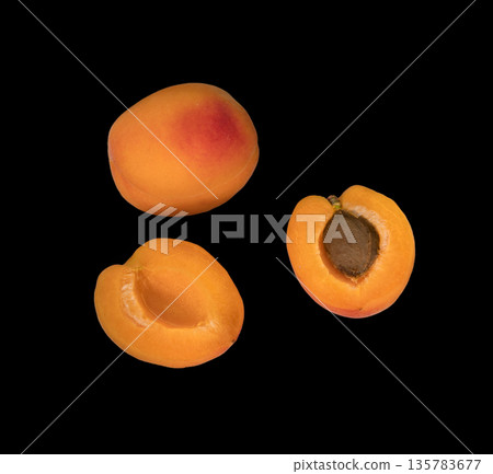 Ripe Apricot fruits, one whole apricot and two divided apricot pieces, on a black background in isolation Ripe Apricot fruits, one whole apricot and two divided apricot pieces, on a black background in isolation 135783677