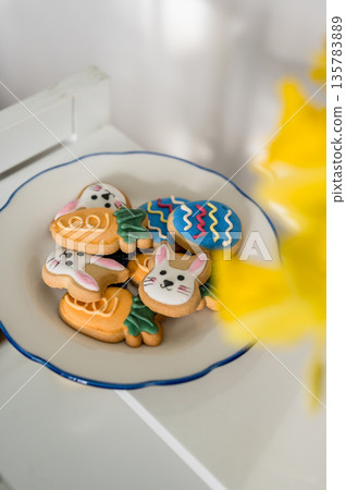 Easter spring background. Easter cookies with colourful icing: bunnies, carrots and eggs in a plate with bouquet of fresh. Bright and airy photo Easter spring background. Easter cookies with colourful icing: bunnies, carrots and eggs in a plate with bouquet of fresh. Bright and airy photo 135783889
