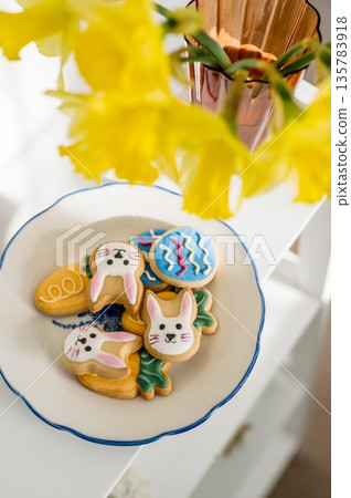 Easter spring background. Easter cookies with colourful icing: bunnies, carrots and eggs in a plate with bouquet of fresh. Bright and airy photo 135783918