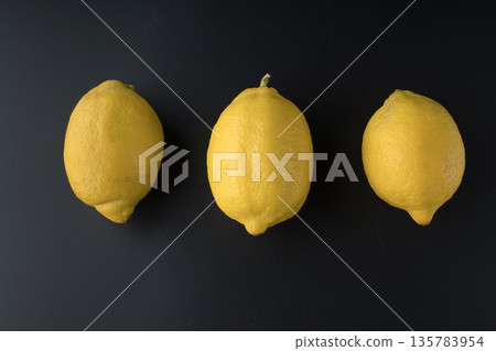 Three whole lemons are arranged in a row on a black background isolated Three whole lemons are arranged in a row on a black background isolated 135783954