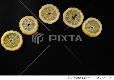Five lemon slices lined up in a semicircle on a black background isolated Five lemon slices lined up in a semicircle on a black background isolated 135783993