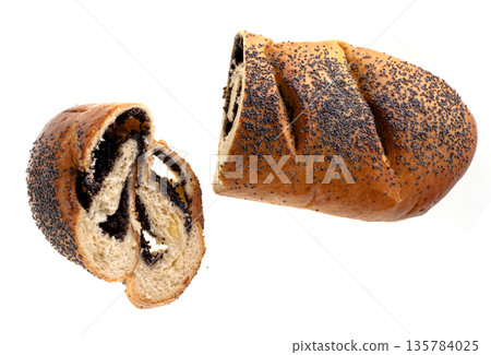 Ruddy loaf sprinkled with poppy seeds and stuffed with poppy seeds, roll, cut into pieces, on a white plate isolated 135784025
