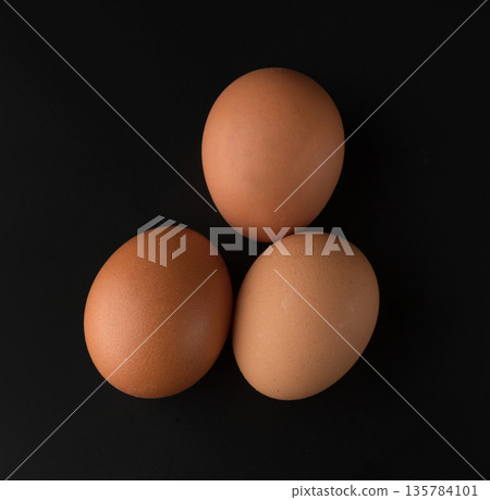 Chicken eggs with brown shell on black background Chicken eggs with brown shell on black background 135784101