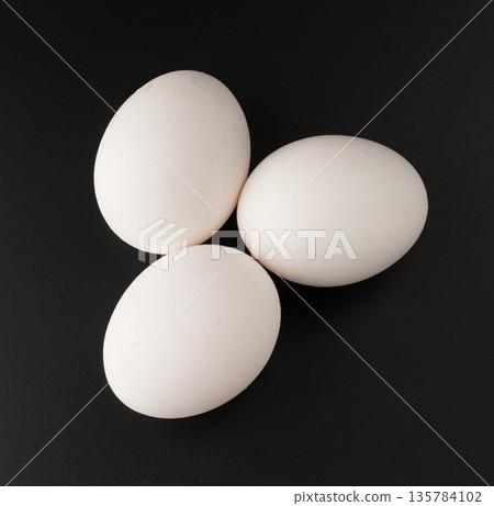 Chicken eggs with white shells on black background isolated Chicken eggs with white shells on black background isolated 135784102