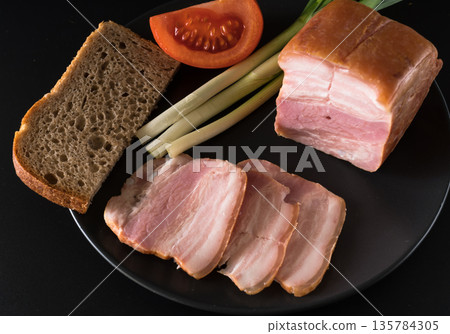 Food, lard, green onions, tomato, black bread, on a black plate on a black background 135784305