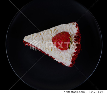Piece of cake covered with protein cream and strawberries on a black plate and black background isolated 135784399