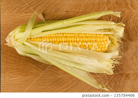 Kachan of young corn, in husks on a wooden board 135784406