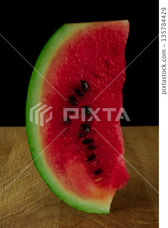 Piece of ripe watermelon on wood board on black background Piece of ripe watermelon on wood board on black background 135784429