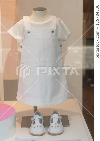 Childrens outfit displayed in a shop window. Minimal and clean retail presentation. Concept of kids fashion, shopping and lifestyle Childrens outfit displayed in a shop window. Minimal and clean retail presentation. Concept of kids fashion, shopping and lifestyle 135784536